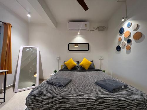 a bedroom with a bed with yellow pillows and a mirror at Whoopers Party Hostel, Palolem in Palolem
