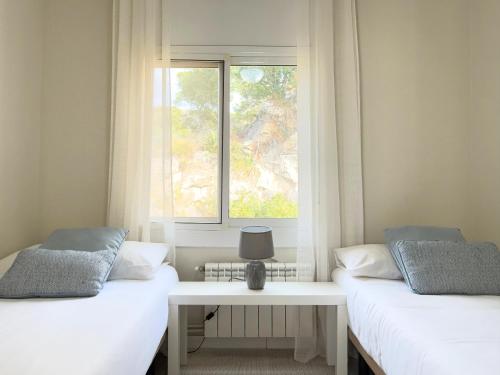 zwei Betten in einem Zimmer mit Fenster in der Unterkunft Atico Isabel in Castelldefels