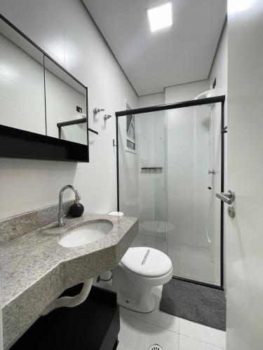 une salle de bain avec toilettes et douche en verre dans l'établissement Refúgio Perfeito no Boqueirão: Apartamento Moderno a 100m da Praia com Sacada Gourmet e Piscina!, à Praia Grande