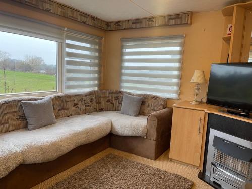 a living room with a couch and a flat screen tv at Caravan 5 by The River Severn, dog friendly, great for contractors, walkers and fishing on the river in Chaceley