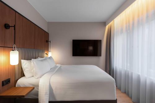 a bedroom with a large white bed and a window at voco Stockholm - Kista by IHG in Stockholm
