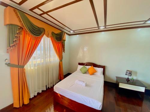 a bedroom with a bed and a window with orange curtains at Princesa Sunset Homes in Puerto Princesa City