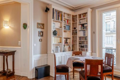 une salle à manger avec une table, des chaises et des étagères dans l'établissement CR57 - Rennes Elegances, à Paris
