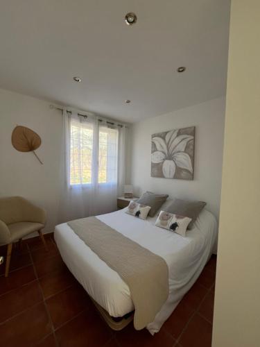 PuyloubierにあるStudio au Pied de la ste Victoireの大きな白いベッドと椅子のある寝室