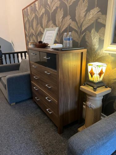 a dresser with a lamp on top of it next to a couch at piccolo Hotel in Glasgow
