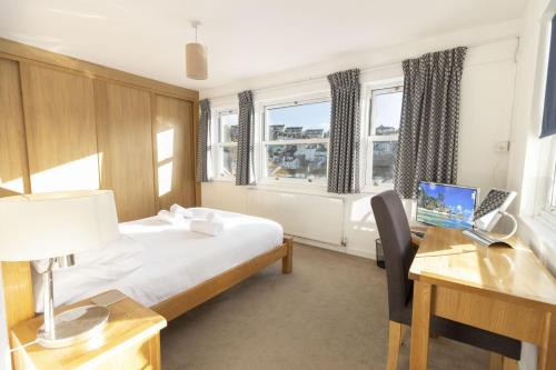 a bedroom with a bed and a desk with a laptop at Apters Hill House Dog Friendly With Free Parking in Brixham