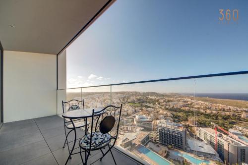 a table and a chair on a balcony with a view at Official Apartments of Mercury Towers by MyMercury in St. Julianʼs