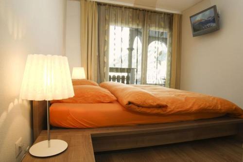 1 cama en un dormitorio con lámpara y ventana en Residenz Ambassador A32 en Leukerbad