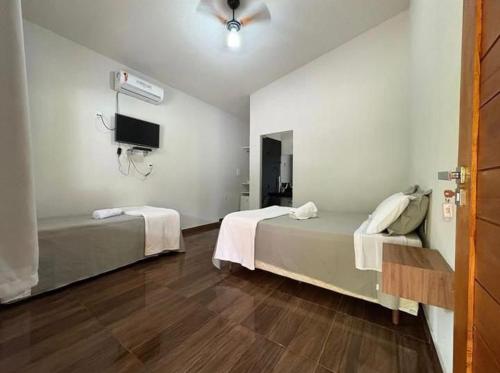 a hotel room with two beds and a tv at Chalés Riacho da Serra Capitólio in Guapé