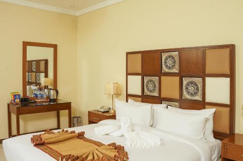 a bedroom with a large white bed with towels on it at Faletti's Grand Hotel Gujranwala in Gujrānwāla