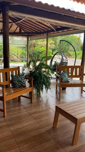 two wooden benches sitting on a patio with a plant at Chalés Riacho da Serra Capitólio in Guapé