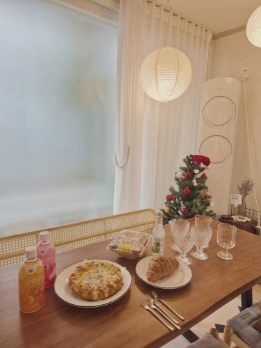a table with two plates of food and a christmas tree at Soban Stay in Busan
