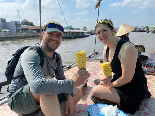 a man and woman sitting on a boat eating ice cream at Miền Tây Hotel in Can Tho
