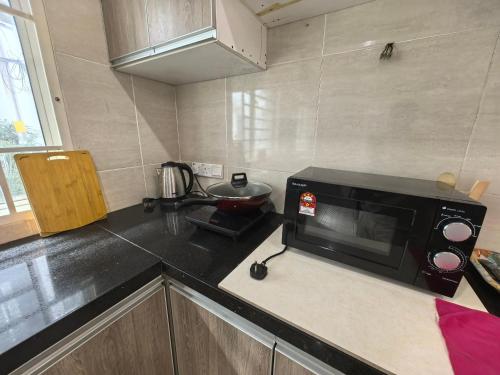 a kitchen with a black microwave on a counter at Langkawi A&A Homestay 13 Pax in Kuah