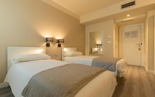 a bedroom with two beds and a mirror at La Dolce Vita Hotel in Menton