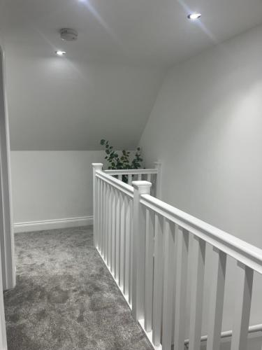 a white hallway with a staircase with a plant at Mill House The Lodge in Upwell
