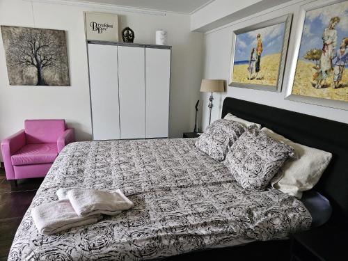 a bedroom with a bed and a pink chair at NamaStee aan Zee in Vlissingen