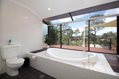 a bathroom with a tub and a toilet and a window at Bella Vista with swimming pool and ocean view in Batemans Bay