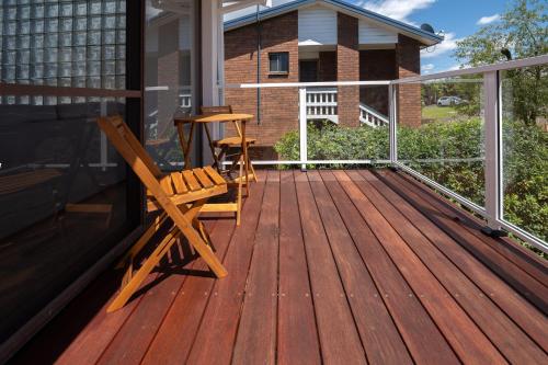 a wooden deck with a chair and a table on it at Bella Vista with swimming pool and ocean view in Batemans Bay