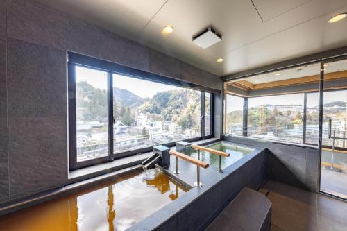 a room with a plunge pool with a large window at Arima Onsen Takayamaso Hanano in Kobe
