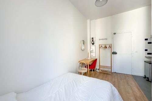 une chambre blanche avec un lit et un bureau dans l'établissement Flexliving - Studio - Parodi, à Paris