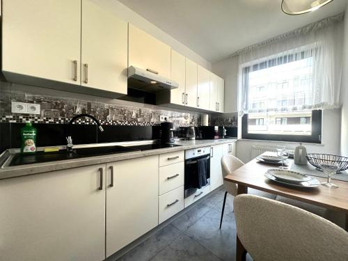 a kitchen with white cabinets and a wooden table at Nyska Apartment - Self Check-In 20h - Parking in Wrocław