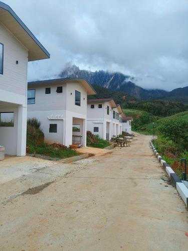 a row of houses on a dirt road with mountains in the background at The Pampines Villa, Mount Kinabalu in Ranau