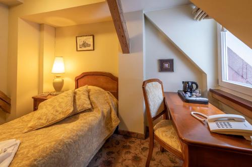 a bedroom with a bed and a desk with a telephone at Willa Barbara - ProHarmonia in Lądek-Zdrój