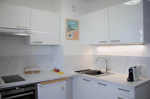 une cuisine blanche avec des armoires blanches et un évier dans l'établissement Face à la Mer YourHostHelper, à Cannes