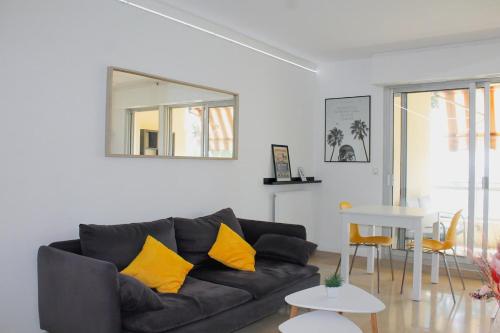 - un salon avec un canapé noir et des oreillers jaunes dans l'établissement Face à la Mer YourHostHelper, à Cannes