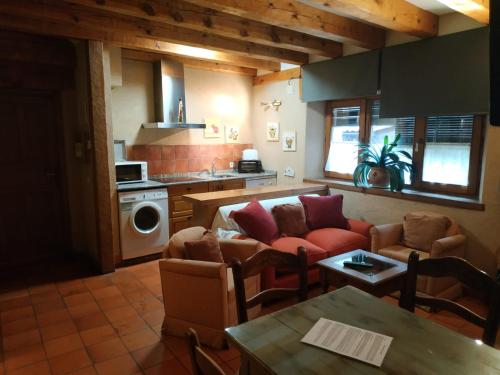 a living room with couches and a table and a kitchen at Apartamentos Lobiche in Navafría
