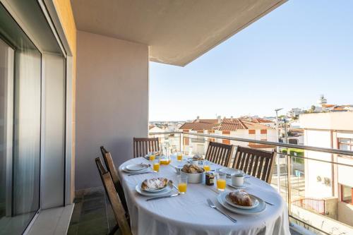a table with plates of food on a balcony at Sunset T3 - by Smarthomes in São Martinho do Porto