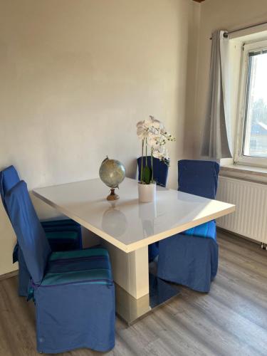 a white table with blue chairs and a vase on it at Gemütliche Wohnung Nahe Therme & Redbull Ring in Leoben
