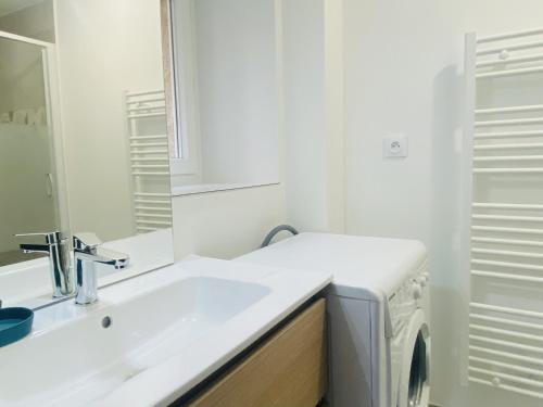 La salle de bains blanche est pourvue d'un lavabo et d'un lave-linge. dans l'établissement La MADELEINE, à Rodez
