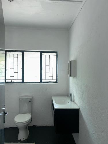 a white bathroom with a toilet and a sink at Miners Rest Lodge in Phalaborwa