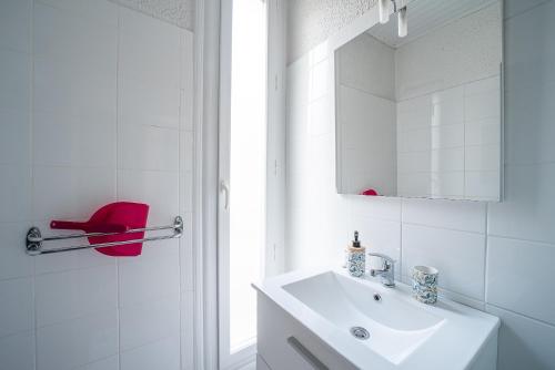 La salle de bains blanche est pourvue d'un lavabo et d'une chaise rouge. dans l'établissement Le Bain d’Amélie - A 200m des Thermes, à Amélie-les-Bains-Palalda