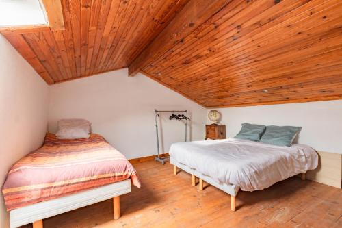 deux lits dans une chambre avec un plafond en bois dans l'établissement Le Coteau Ensoleillé - Climatisée avec piscine, à Carcassonne