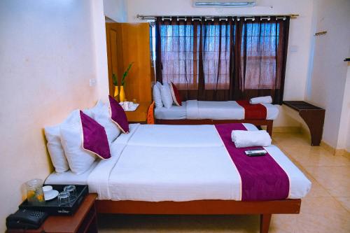 a hotel room with two beds and a window at Naksha Tree Hotels Kishore Inn - Koyambedu in Chennai