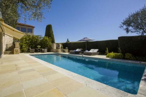 une piscine dans une cour avec un parasol dans l'établissement Les Moines, à Mougins