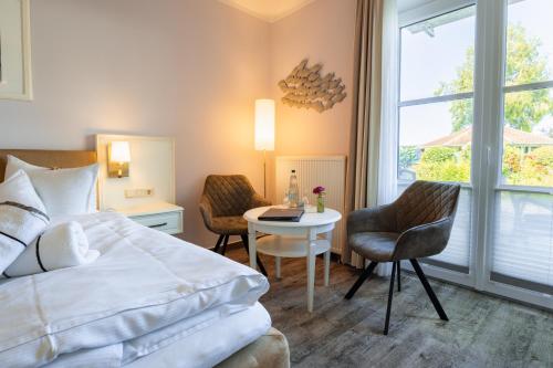 a hotel room with a bed and a table and chairs at Hotel Wilhelmshöhe in Warnemünde