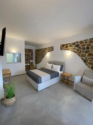 a bedroom with a bed and a couch and a chair at Trocadero Ermioni Suites in Ermioni