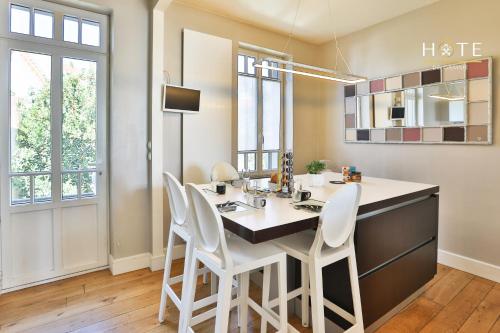 une cuisine avec une grande île et des chaises blanches dans l'établissement Villa luxueuse en bord de mer, à Les Sables-dʼOlonne