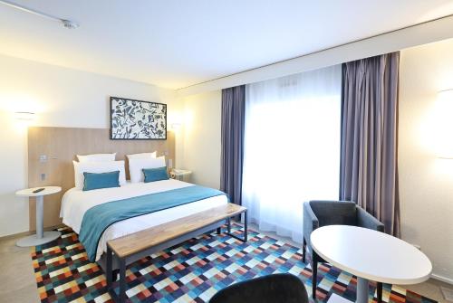 a hotel room with a bed and a table and chairs at Mercure Grenoble Centre Porte des Alpes in Grenoble