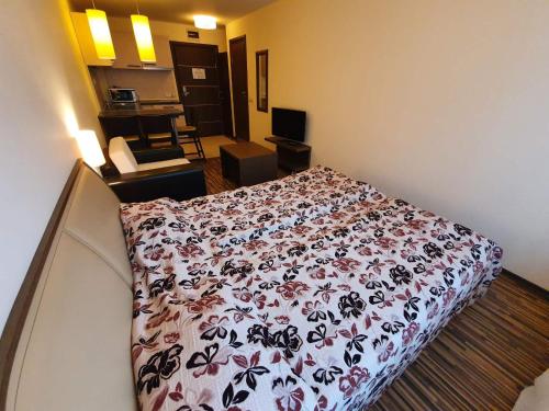 a hotel room with a bed with a flowered blanket at Bansko lodge 500m from ski lift in Bansko