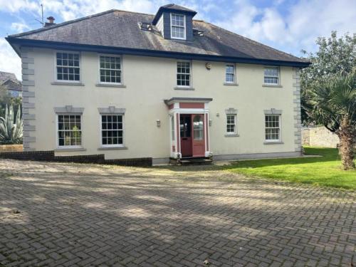 a white house with a red door and a driveway at Finest Retreats - Nicely Tucked Away Cottage in Torpoint