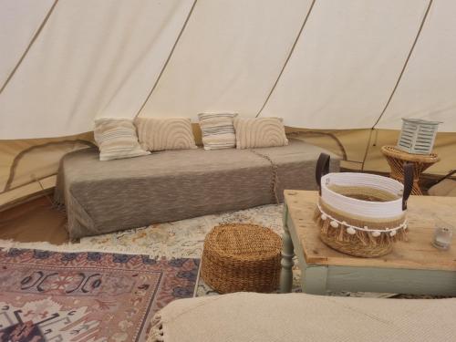 a tent with a couch and a table in a room at Tente glamping "bluebird" à la Ferme de la Chevêche in Fosses-La-Ville