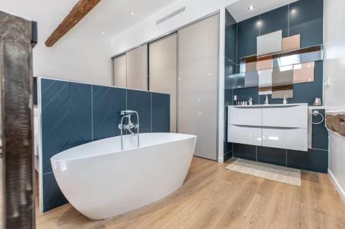 La salle de bains est pourvue d'une grande baignoire blanche et de carrelage bleu. dans l'établissement Apartement Forville by Halldis, à Cannes