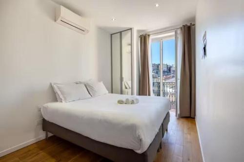 une chambre avec un grand lit et une grande fenêtre dans l'établissement Apartement Forville by Halldis, à Cannes
