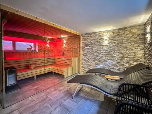 a room with a bench and a tv and a stone wall at Our's Living - modern Apartments with Sauna near Kitzbüheler Alpen ski lift in Hollersbach im Pinzgau