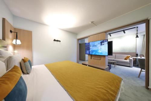 a hotel room with a bed and a flat screen tv at Mercure Grenoble Centre Porte des Alpes in Grenoble
